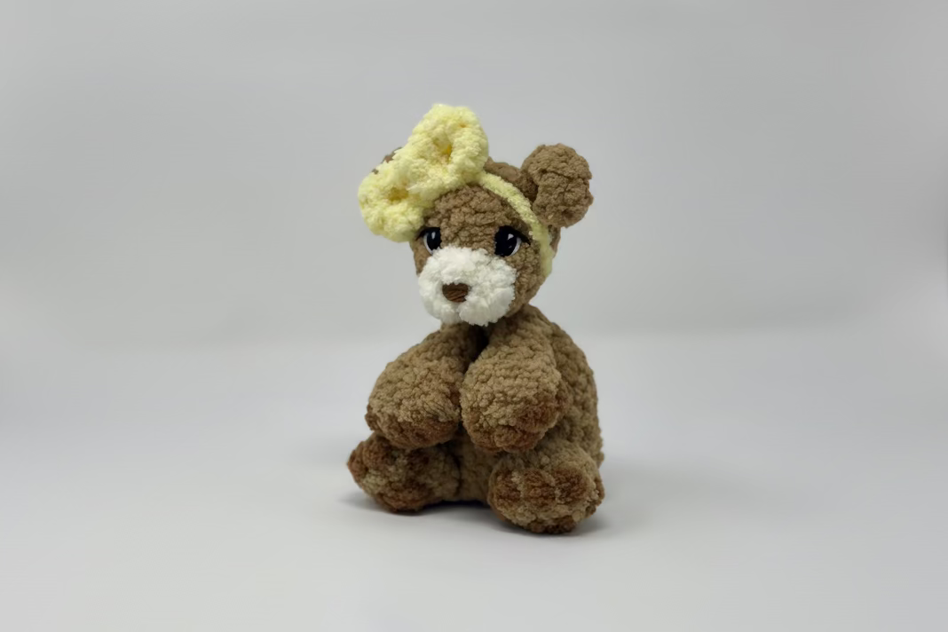 Brown teddy bear with a yellow bow on a white background
